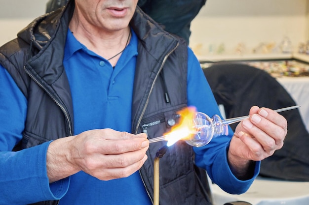 Un artesano de vidrio muestra el arte de hacer cristalería en el mercado callejero