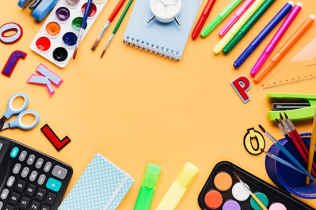 Foto gratuita artículos de papelería y oficina colocados en mesa naranja.