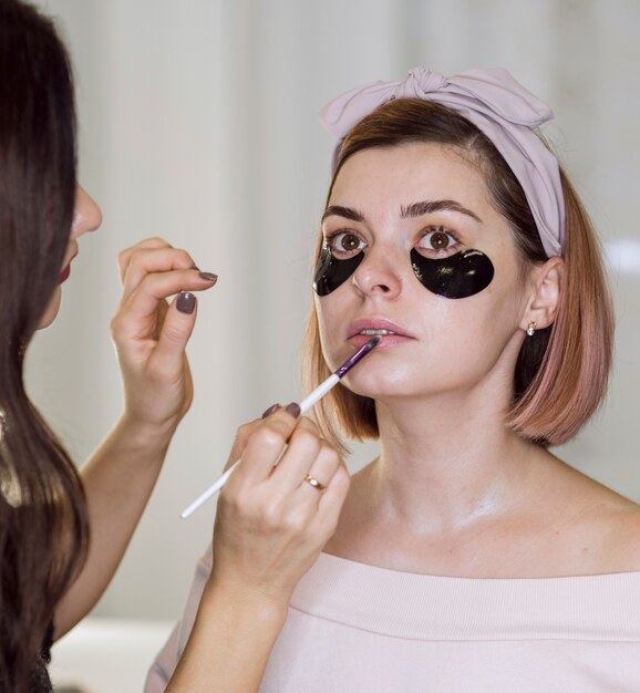 Artista aplicando lápiz labial en mujer natural