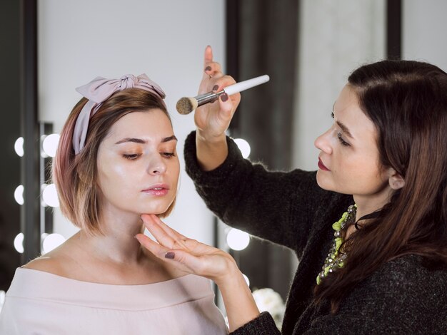 Artista aplicando polvo en mujer encantadora