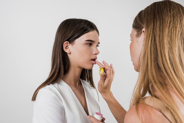 Artista aplicando protector labial en el modelo