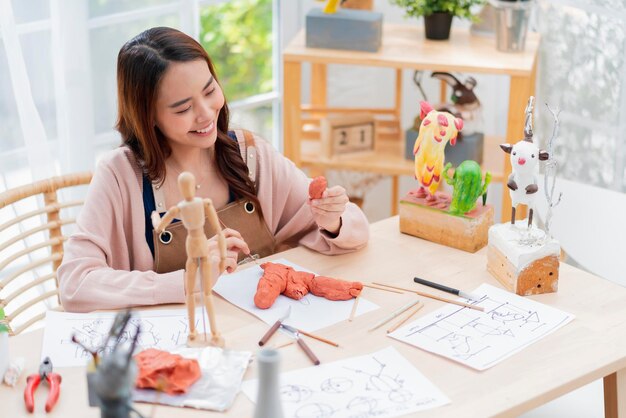 La artista asiática, una escultura de arcilla de arttoys, pasa el día de fin de semana para su pasatiempo de escultura de arcilla, define adecuadamente la forma de la anatomía de la cara mientras hace la estatua de arcilla en el estudio de casa, un estilo de vida informal en casa