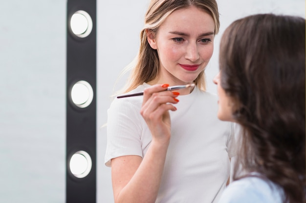 Artista de belleza femenina aplicando maquillaje en modelo