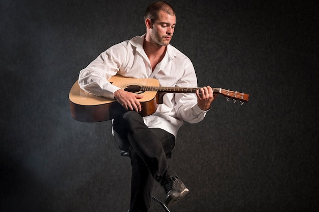 Foto gratuita artista en camisa blanca tocando la guitarra tiro largo