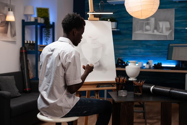 Artista creativo dibujando sobre lienzo trabajando en la sombra del boceto usando lápiz gráfico durante la lección de arte en el taller creativo del hogar. Estudio artístico con herramientas de dibujo profesionales. Concepto de lección de pintura