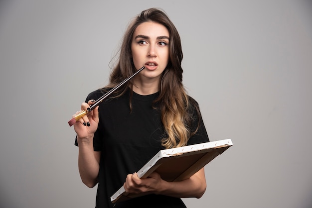 Artista femenina en camisa negra tocando su boca con un cepillo.