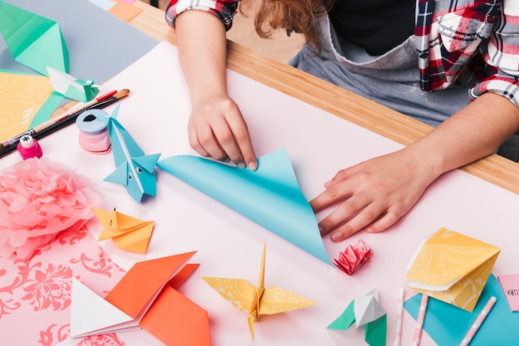 Foto gratuito artista femenina doblando papel de origami para hacer bellas artesanías.