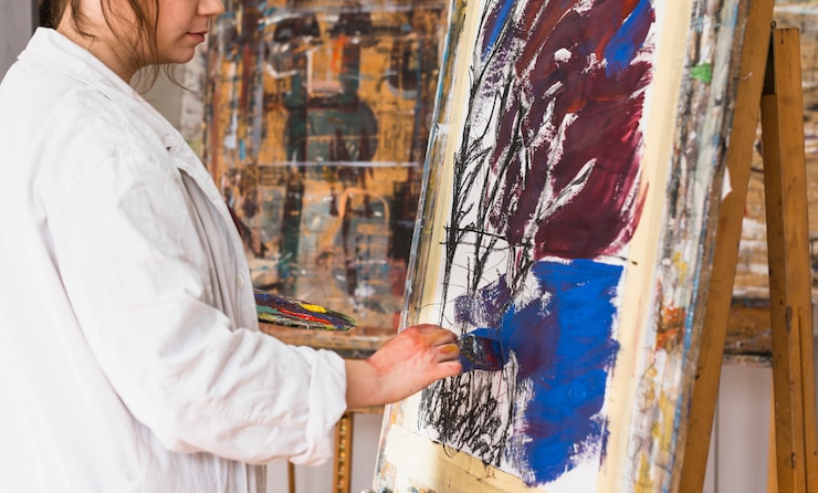 Foto gratuito artista femenina pintando con pincel sobre lienzo en taller