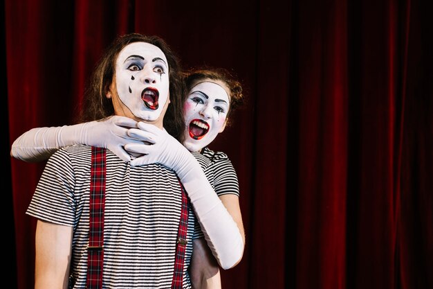 Artista femenino del mime que agarra el cuello del mime masculino