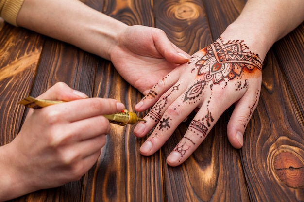 Artista haciendo mehndi en mano de mujer