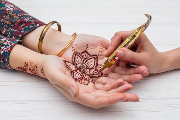 Artista haciendo mehndi en las palmas de las mujeres.