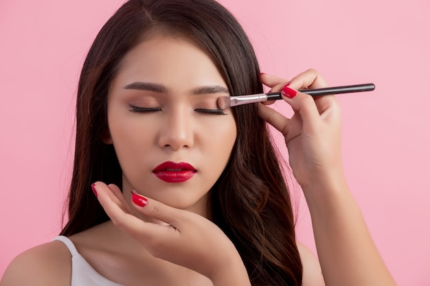 Artista de maquillaje aplicando delineador líquido con pincel.