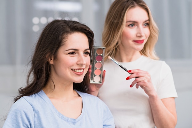 Artista de maquillaje femenino que muestra la paleta de sombra de ojos con estilo