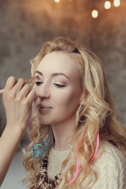 Artista de maquillaje con hermosa mujer rubia