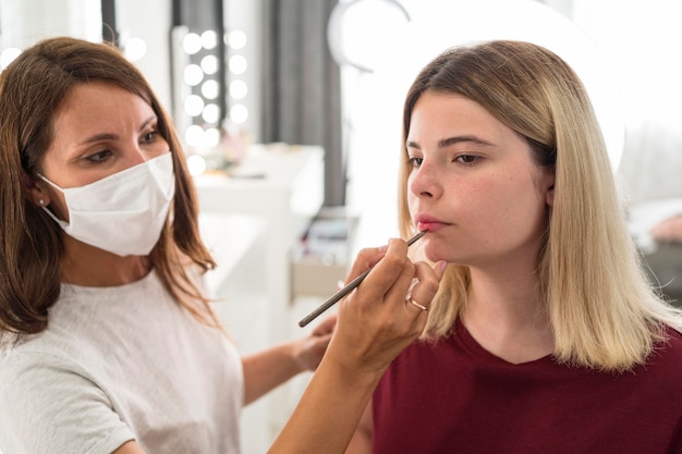 Artista de maquillaje con máscara médica y cliente