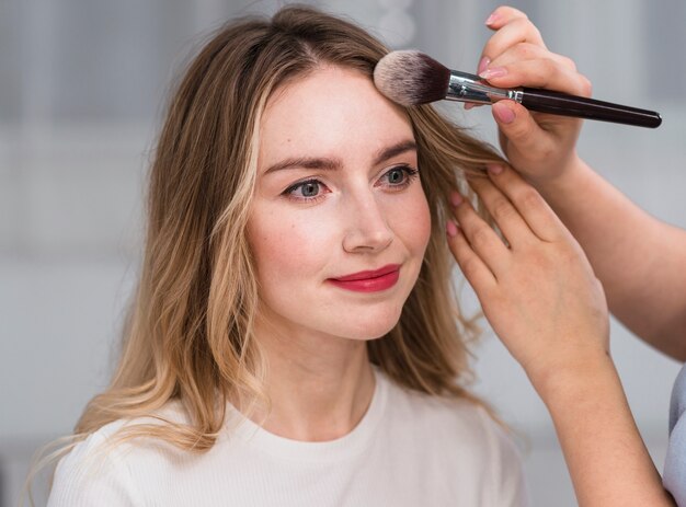 Artista de maquillaje en polvo frente a mujer