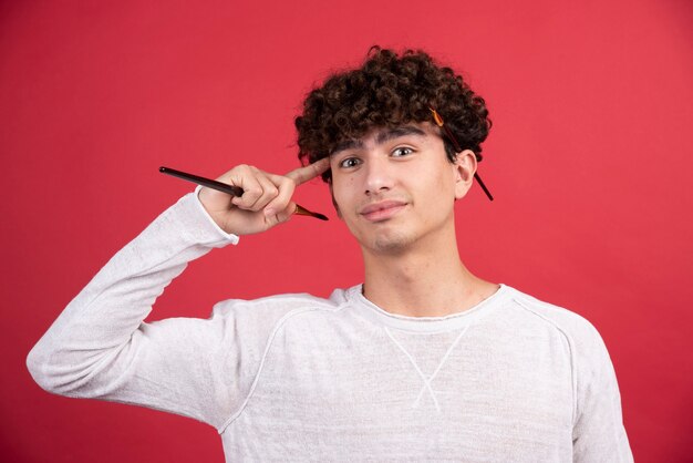 Artista masculino joven mirando a la cámara con pinceles.