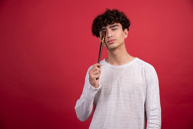 Artista masculino joven posando con pinceles.