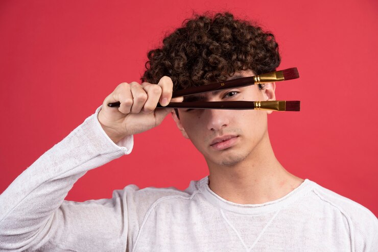 Foto gratuito artista masculino joven posando con pinceles.