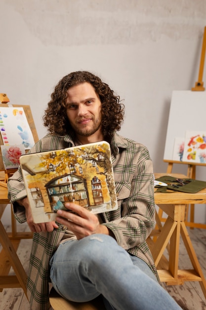 Artista masculino pintando en estudio con acuarelas.