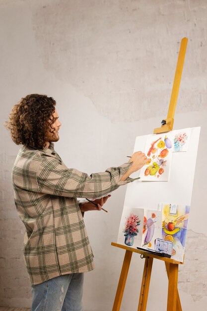 Artista masculino pintando en estudio con acuarelas.