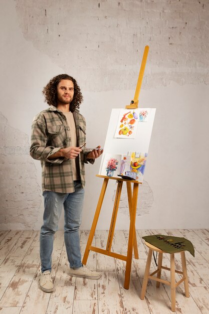 Artista masculino pintando en estudio con acuarelas.