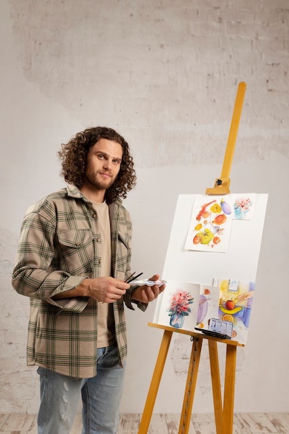 Artista masculino pintando en estudio con acuarelas.