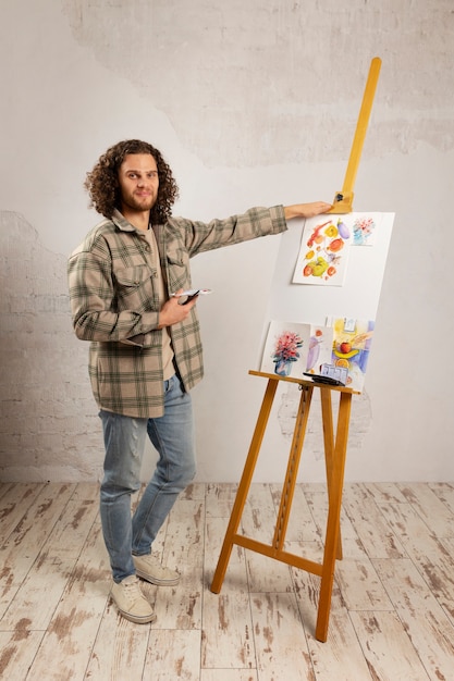 Artista masculino pintando en estudio con acuarelas.