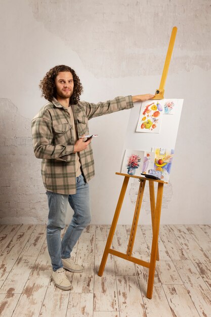 Artista masculino pintando en estudio con acuarelas.