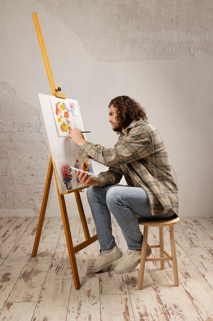 Artista masculino pintando en estudio con acuarelas.