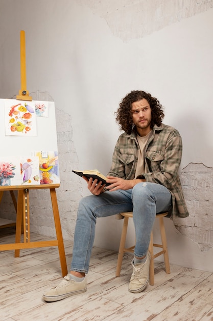 Artista masculino pintando en estudio con acuarelas.