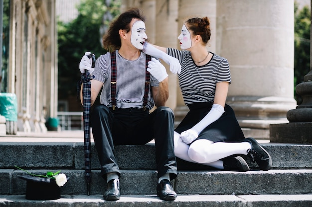 Artista de mimo masculino y femenino sentado en la escalera