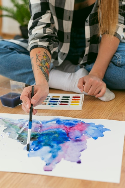 Foto gratuita artista mujer pintando en el piso vista alta