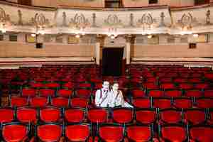 Foto gratuita artista de la pareja de mimos sentados juntos en la silla en el auditorio