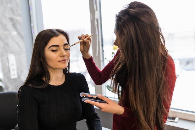 Artista profesional pone maquillaje en polvo en los párpados modelo