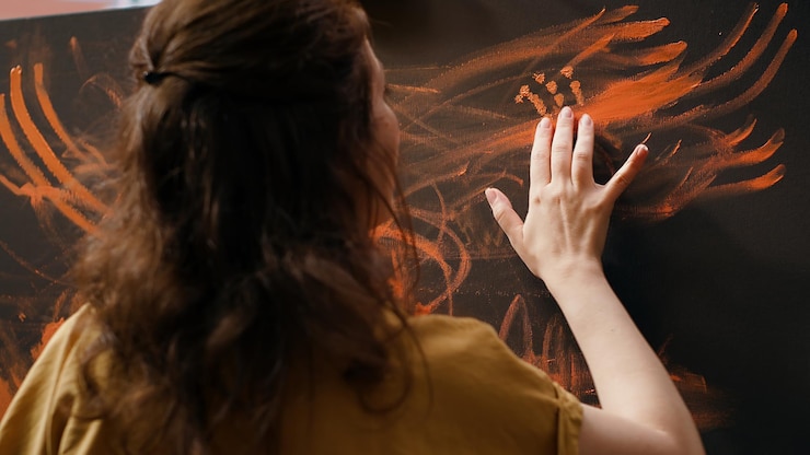 Foto gratuito artista segura de sí misma de pie ante un caballete y pintando con sus dedos