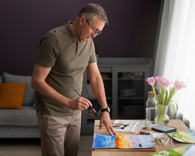 Artista senior en el estudio pintando con acuarela.