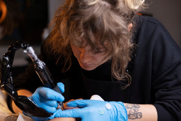 Artista del tatuaje de alto ángulo trabajando