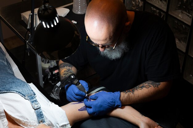 Artista de tatuaje experimentado trabajando en el tatuaje del cliente