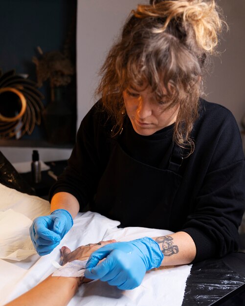 Artista del tatuaje con guantes de alto ángulo