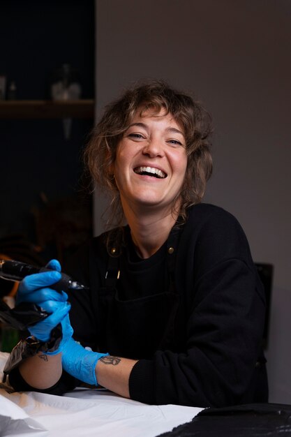 Artista del tatuaje sonriente de tiro medio en el interior