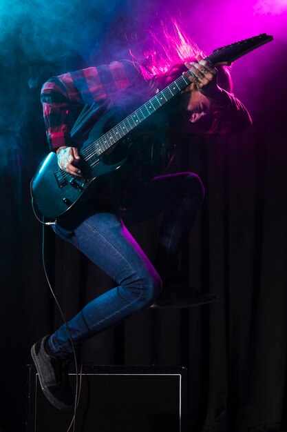 Artista tocando la guitarra y saltando hacia los lados