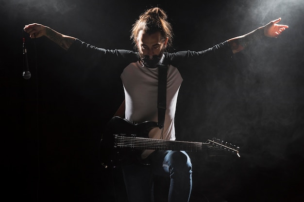 Artista tocando la guitarra y sosteniendo un micrófono