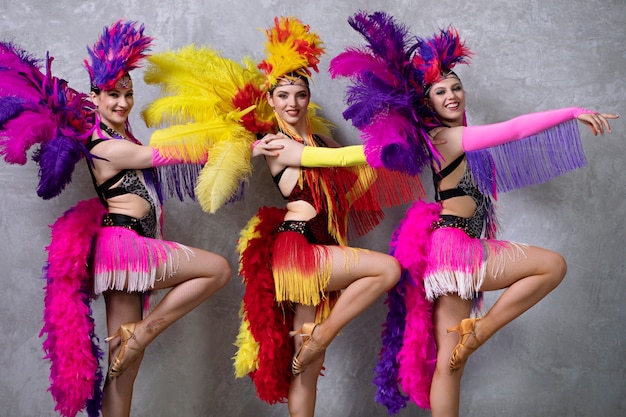 Artistas de cabaret femenino bailando entre bastidores en trajes de plumas