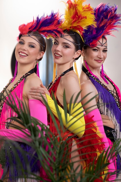 Artistas femeninas de cabaret posando entre bastidores con trajes de plumas
