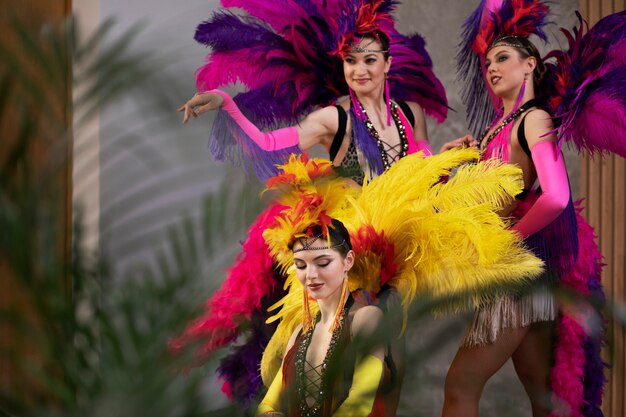 Artistas femeninas de cabaret posando entre bastidores con trajes de plumas