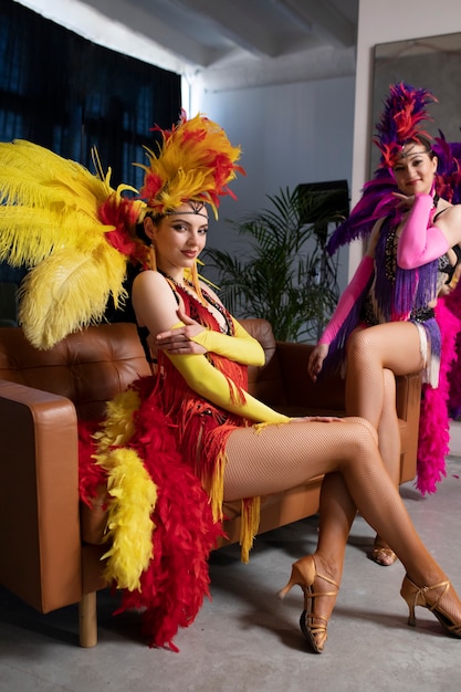 Artistas femeninas de cabaret posando entre bastidores con trajes de plumas