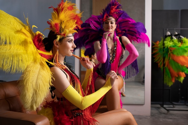 Artistas femeninas de cabaret posando entre bastidores con trajes de plumas