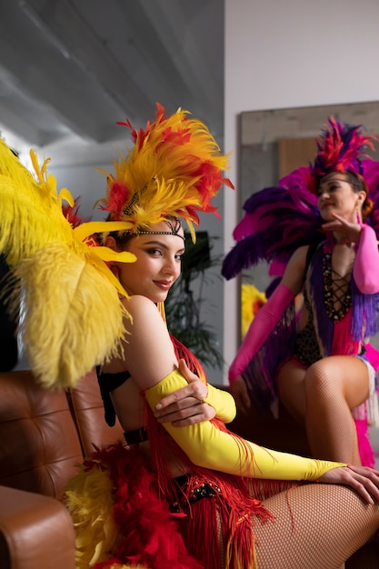 Artistas femeninas de cabaret posando entre bastidores con trajes de plumas