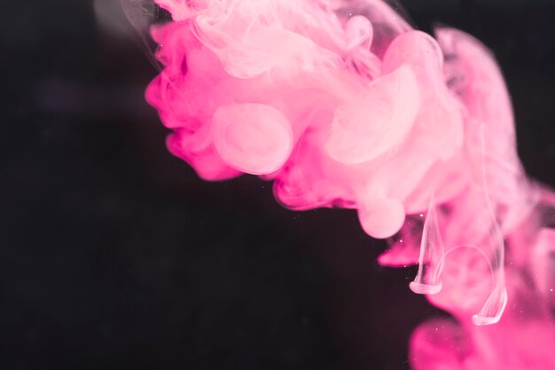 Artístico humo rosa potente en pantalla negra.